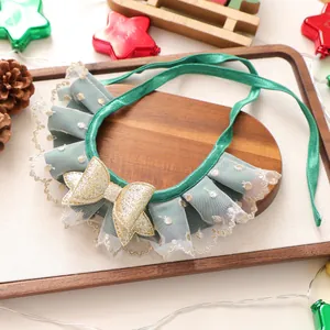 Détail d'un collier de Noël pour animaux avec ruban vert foncé, dentelle et nœud doré