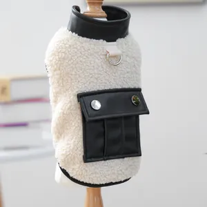 Detail of soft white fleece pet vest with black leather pockets and silver metal D-ring