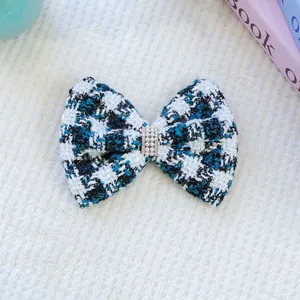 Détail d'un nœud papillon en tweed avec perles et strass sur un tissu doux blanc