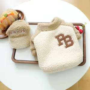 Détail du gilet en polaire pour animaux avec broderie PB sur un plateau en bois