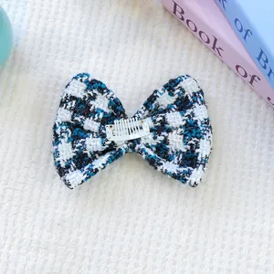 Gros plan d'une barrette noeud en tweed bleu et blanc pour chien avec peigne en métal
