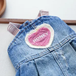 Dettaglio di un abito in denim per cani con ricamo a cuore rosa e scritta Honey