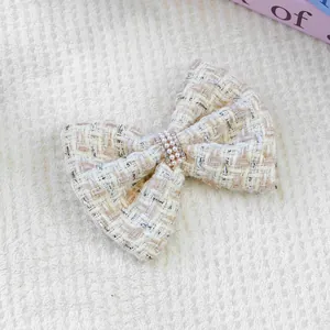 Détail de la pince à cheveux noeud en tweed avec perles et strass pour chiens et chats