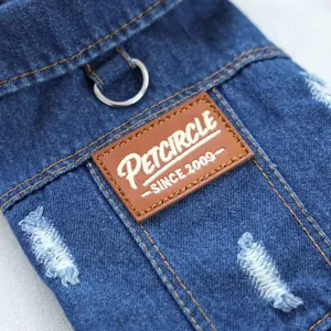 Close-up of denim pet jacket featuring leather label with D-ring and distressed details