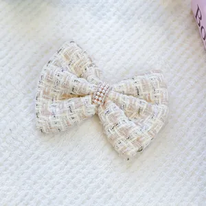 Gros plan sur une pince à cheveux pour animaux en tweed blanc avec des perles élégantes