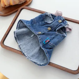 Dettaglio dell'abito in denim per cani con tessuto blu, bottoni metallici e spalline rosa