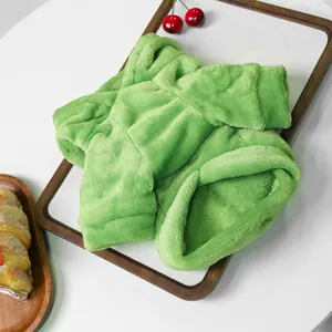 Detailed flat lay of soft green flannel pet clothes on a wooden tray with bright lighting