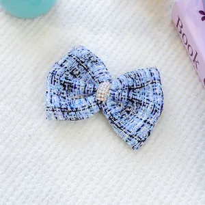 Gros plan d'un nœud papillon en tweed bleu pour chien avec perles et strass sur fond peluche