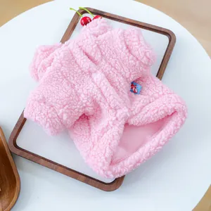 Detail van roze sherpa fleece huisdierentrui met drukknopen op een houten dienblad
