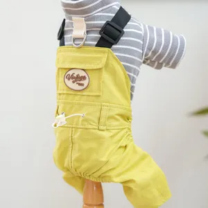 Close-up of yellow canvas pet overalls with vintage patch and grey striped knit shirt