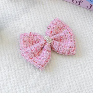 Détail d'une pince à cheveux en tweed rose pour animaux avec perles et strass brillants