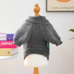 Close-up of grey knit pet sweater featuring chunky cable pattern and blue side label