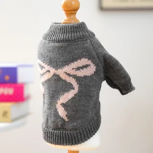 Detail of grey knitted pet sweater with pink bow pattern on a wooden mannequin