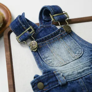 Close-up of vintage denim pet overalls featuring brass buttons and orange contrast stitching