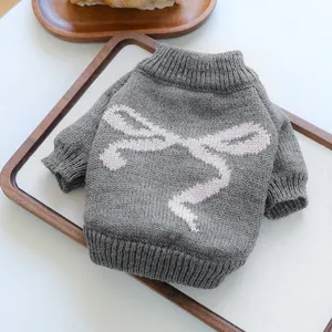Gray knitted pet sweater with pink bow pattern for small dogs and cats on a wooden tray