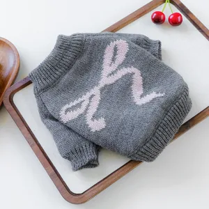 Detail of grey knitted pet sweater featuring pink bow pattern and ribbed neck trim