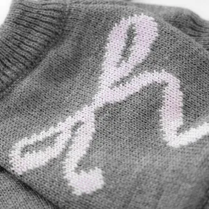 Macro detail of soft grey knit pet sweater showing pink letter pattern and ribbed hem