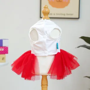 Detail of pet dress with white vest, red mesh skirt and three buttons on wooden stand