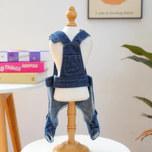 Close-up of dark blue pet denim overalls with pocket and button detail on a white model