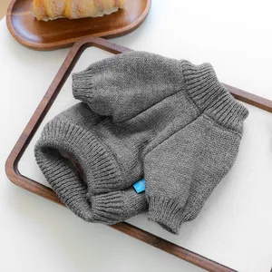 Detailed knit texture of a gray pet sweater with ribbed cuffs on a wooden background