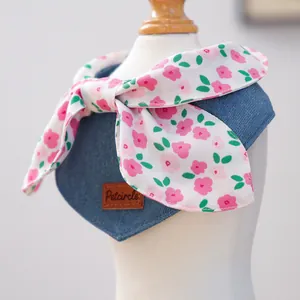 Close-up of denim pet bandana with a floral bow tie and leather brand tag