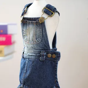 Detail of blue denim pet overalls featuring metal buckles and textured jeans fabric