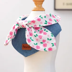 Detail of blue denim pet bandana with floral bow and brown leather Petcircle tag