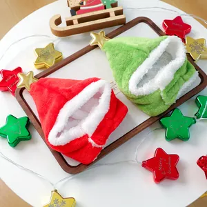 Macro detail of red and green plush Christmas pet hats with gold stars on a festive tray