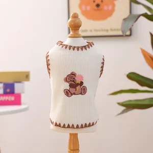 Crèmefarbene Hundeweste mit Bärenstickerei und rosa Eiscreme-Detail auf Holzständer