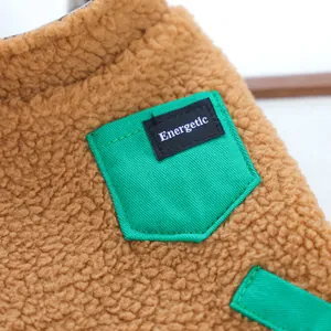 Dettaglio del gilet in pile marrone per cani con tasca verde e scritta decorativa