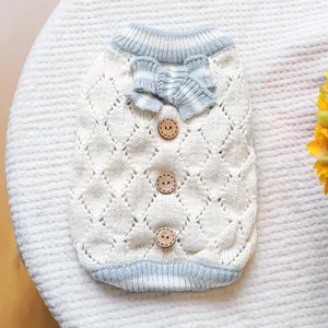 Detail of white hollow knit pet sweater featuring blue bow and wooden buttons