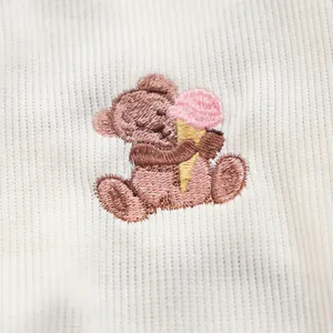 Detailaufnahme der Bärenstickerei mit Eiscreme auf weißem Cordstoff der Haustierweste
