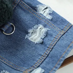 Close-up of denim pet jacket with distressed details, metal D-ring and green sherpa lining