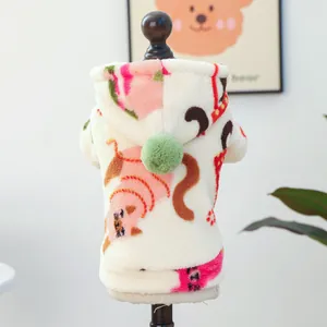 Detail of warm beige pet hoodie with fleece texture, cartoon prints and a green pom-pom