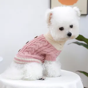 Side view of a small white dog wearing a cozy pink cable-knit sweater with buttons.