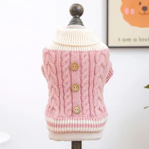 Close-up of pink cable-knit dog sweater featuring white trim and wooden button details