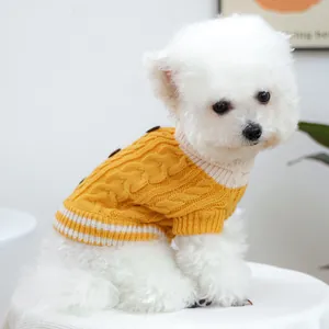 Detalle de suéter de punto amarillo para perro con patrón de trenzas y rayas blancas