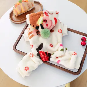 Detalle de mono de forro polar beige para mascotas con flores y capucha con pompón verde