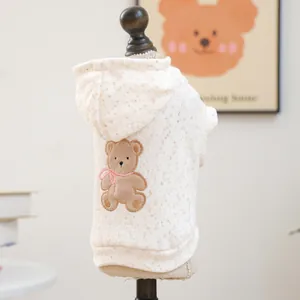 Detail of cream plush pet hoodie featuring cute brown bear embroidery and star patterns
