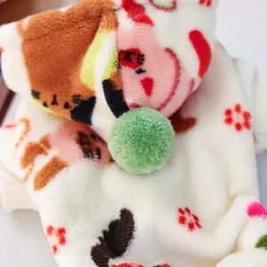 Detalle macro de ropa suave para mascotas con dibujos de gatos y pompón verde