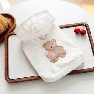 Cute beige puppy hoodie with bear embroidery and leash D-ring on wooden display