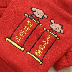 Detail of red fleece festive pet coat featuring cute dog embroidery and golden scroll text