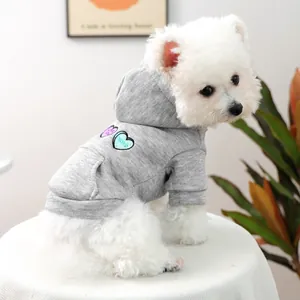 Detail of grey pet hoodie with heart embroidery and mini pocket on a small white dog