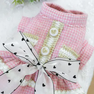 Détail d'une robe rose pour animaux à motif pied-de-poule avec boutons et nœud