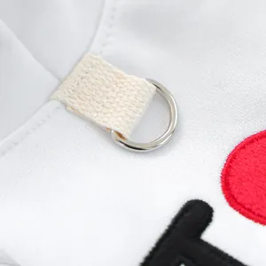 Vue macro détaillée de l'anneau en D métallique sur ce pull blanc chaud pour chiot