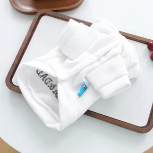 Détail d'un sweat pour animaux blanc avec boutons-pression et poignets côtelés sur plateau