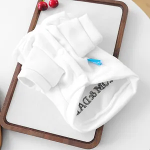 Détail d'un sweat blanc pour animaux avec broderie, étiquette tissée et bouton-pression