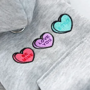 Macro detail of gray pet hoodie featuring three colorful heart embroidery and metal D-ring