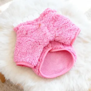 Dettaglio del gilet in pile rosa per animali con bordo bianco su sfondo di peluche