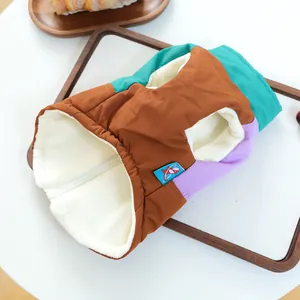 Dettaglio gilet a quadri per cani con fodera in pile e chiusura a zip su vassoio in legno
